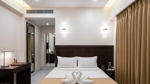 A hotel room with a bed, bedside tables, a desk, and a mirror. - Hotel Maharaja Galaxy (Kolkata)