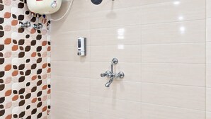 A bathroom with a shower, a water heater, and a soap dispenser. - Hotel Maharaja Galaxy (Kolkata)