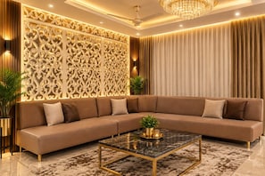 A modern living room with a sectional sofa, a marble coffee table, and decorative wall panels. - Hotel Maharaja Galaxy (Barakpur)