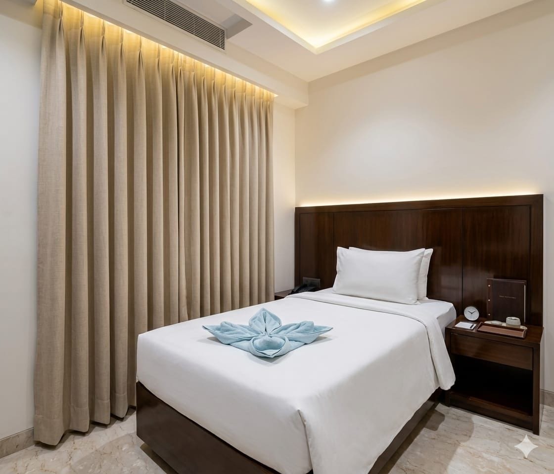 Una habitación de hotel con cama, cortinas, mesita de noche y mesilla auxiliar.