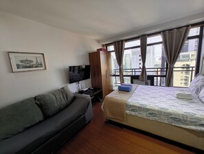 A hotel room with a bed, a sofa, a television, and a window with curtains. - A Cozy Unit with Hotel-Like Luxury Amenities & Near Mall (Makati City)