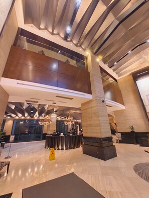 A spacious lobby with a high ceiling, modern lighting fixtures, and a reception desk. - A Cozy Unit with Hotel-Like Luxury Amenities & Near Mall (Makati City)