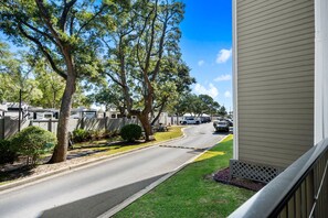 A residential street with parked RVs and cars, trees lining the road, and a house with a visible balcony. - A143 at The Myrtle Beach Resort (Myrtle Beach)
