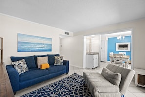 A living room with a blue sofa, a grey armchair, and a patterned rug. - A143 at The Myrtle Beach Resort (Myrtle Beach)