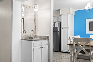 A kitchen with a granite countertop, stainless steel appliances, and a blue accent wall. - A143 at The Myrtle Beach Resort (Myrtle Beach)