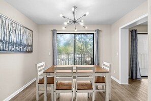 A dining area with a wooden table and chairs, a modern chandelier, and a large window with curtains. - A241 at The Myrtle Beach Resort (Myrtle Beach)