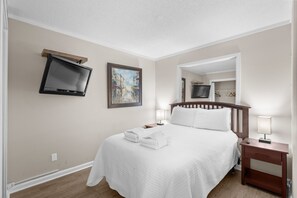 A neatly arranged hotel room with a bed, two bedside tables, a TV mounted on the wall, and a painting. - A241 at The Myrtle Beach Resort (Myrtle Beach)