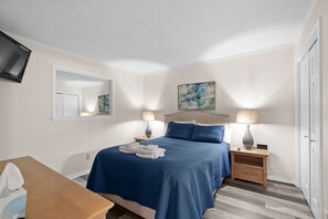 Ein Schlafzimmer mit einem Bett, Nachttischen, einem Spiegel und einem Bild an der Wand.