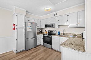 A modern kitchen with white cabinetry, stainless steel appliances, and a granite countertop. - A540 at  The Myrtle Beach Resort (Surfside Beach)