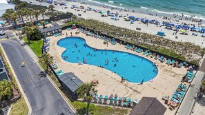 Un área de piscina con varias piscinas, rodeada de sillas de playa y sombrillas.