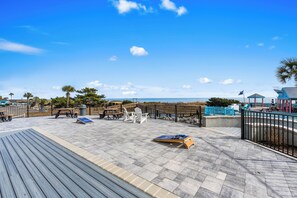 Une terrasse en bois avec des sièges extérieurs, une vue sur la plage et un belvédère.
