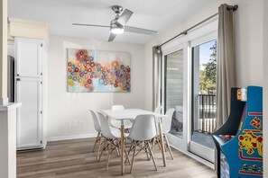 A dining area with a table and chairs, a ceiling fan, a colorful abstract painting, and a view through a glass door. - A129 at the Myrtle Beach Resort (Myrtle Beach)