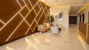 A modern reception area with a wooden wall, a reception desk, a sofa, and a coffee table. - Vogue, Reflection near Reem Central Park & Beach (Abu Dhabi)