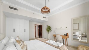 A hotel room with a large bed, a desk, a chair, a mirror, and a wardrobe. - Vogue, Reflection near Reem Central Park & Beach (Abu Dhabi)