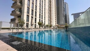 A swimming pool with a modern building in the background. - Vogue, Reflection near Reem Central Park & Beach (Abu Dhabi)