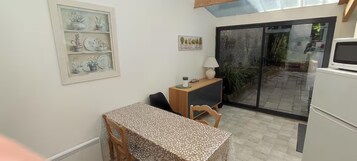 Una pequeña kitchenette equipada con refrigerador, microondas y una mesa de madera con mantel estampado.
