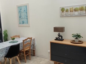 Uma sala de jantar com mesa, cadeiras, luminária e um armário com gavetas.