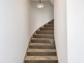 A spiral staircase with a light fixture above it.