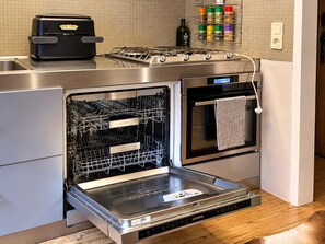 A kitchen with a built-in dishwasher, oven, and a coffee maker on the countertop.