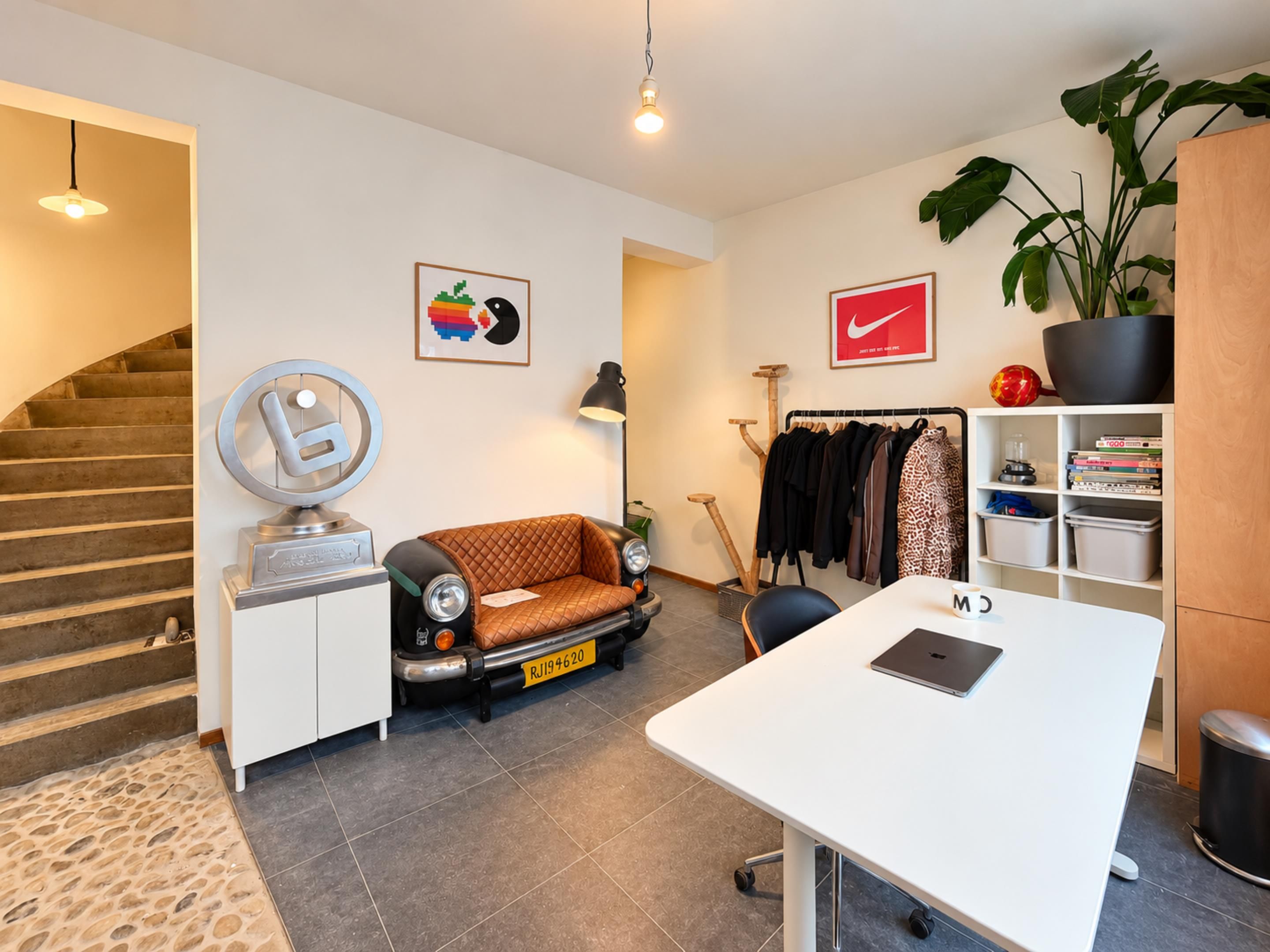 A modern living space with a sofa, a desk, a coat rack, and a staircase.