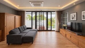Un salon moderne avec un canapé d’angle, un téléviseur à écran plat et une porte-fenêtre coulissante donnant sur un balcon.
