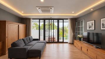 A modern living room with a sectional sofa, a flat-screen TV, and a sliding glass door leading to a balcony.