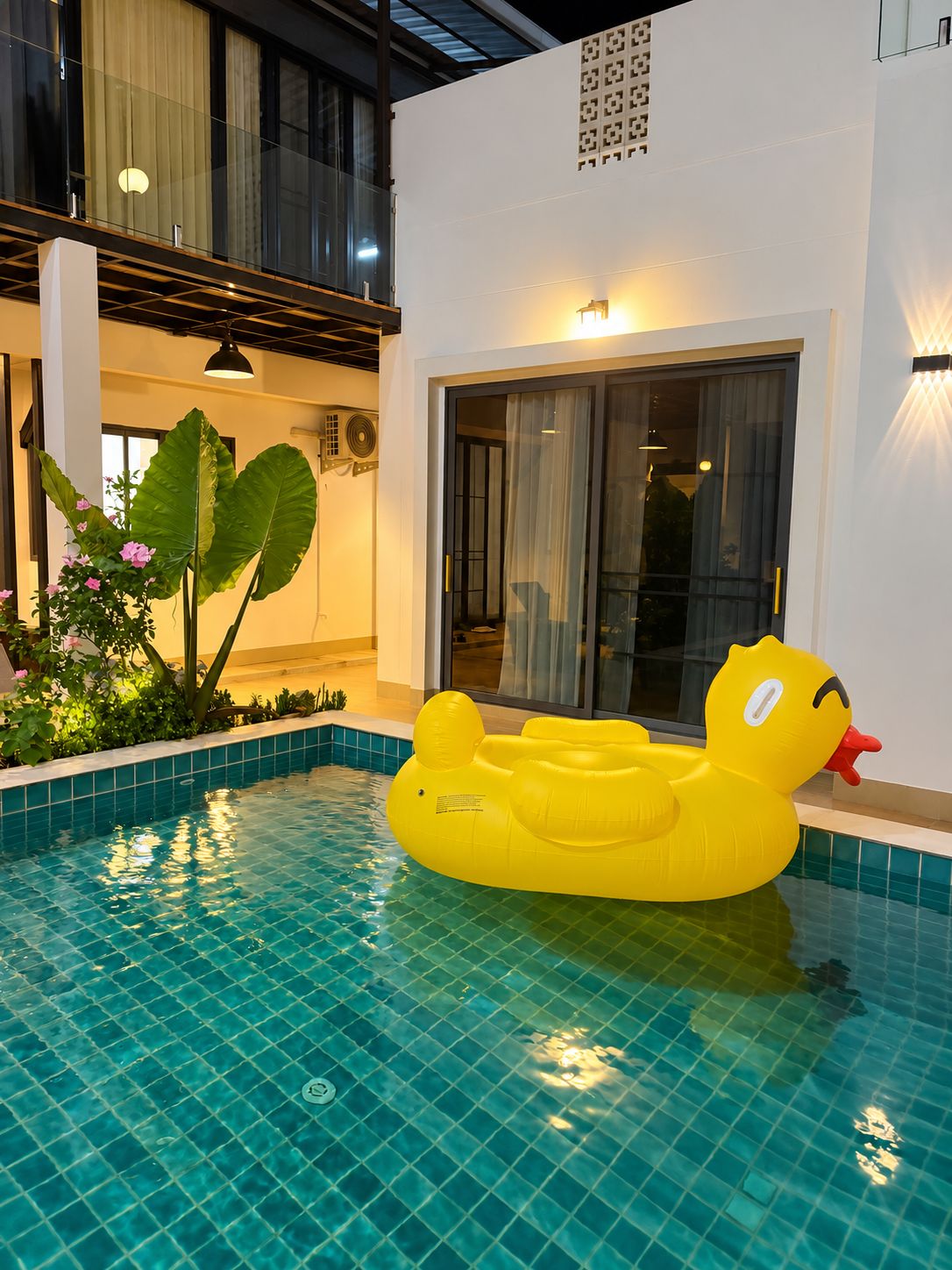 A swimming pool with a yellow inflatable duck float, indoor plants, and a modern interior design.