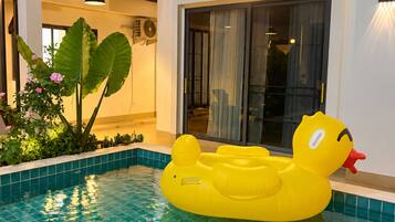 A swimming pool with a yellow inflatable duck float, indoor plants, and a modern interior design.