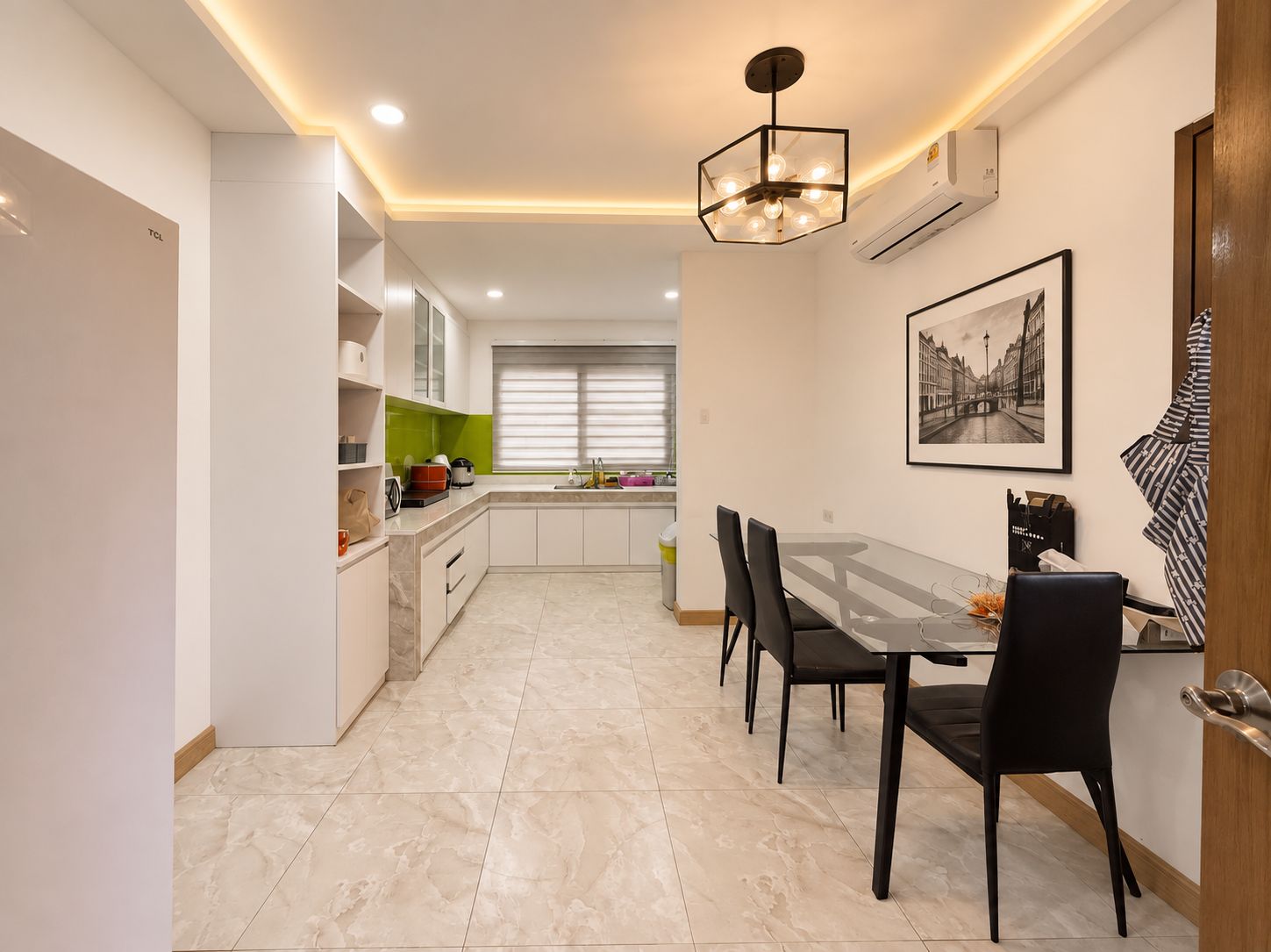 A modern kitchen with a dining area, featuring a table with chairs, a pendant light, and a framed picture on the wall.