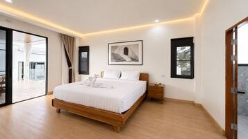 A modern bedroom with a large bed, a nightstand, a framed picture, and a sliding glass door leading to an outdoor area.