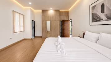 Habitación de hotel con una cama grande, suelo de madera, un armario, un espejo y un cuadro en la pared.