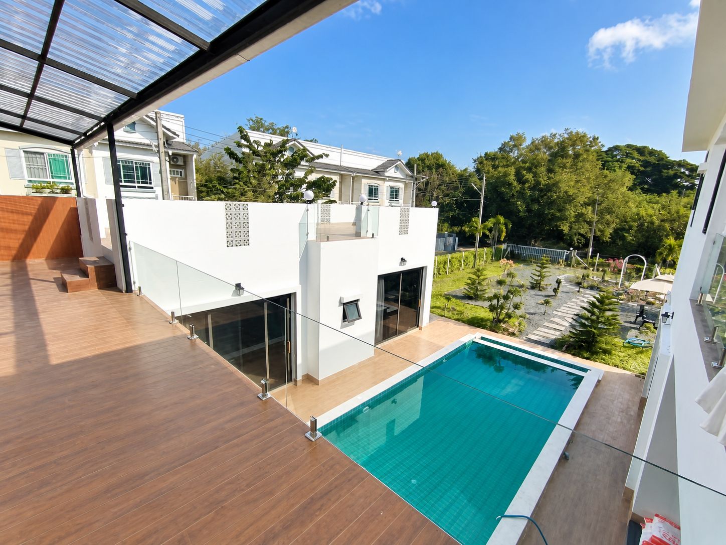 Un edificio moderno con piscina en la azotea, barandillas de vidrio y vistas a una zona residencial.