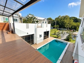 A modern building with a rooftop pool, glass railings, and a view of a residential area.