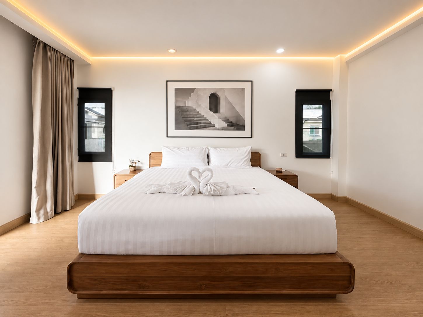 A hotel room with a large bed, a framed picture above the bed, and two bedside tables.