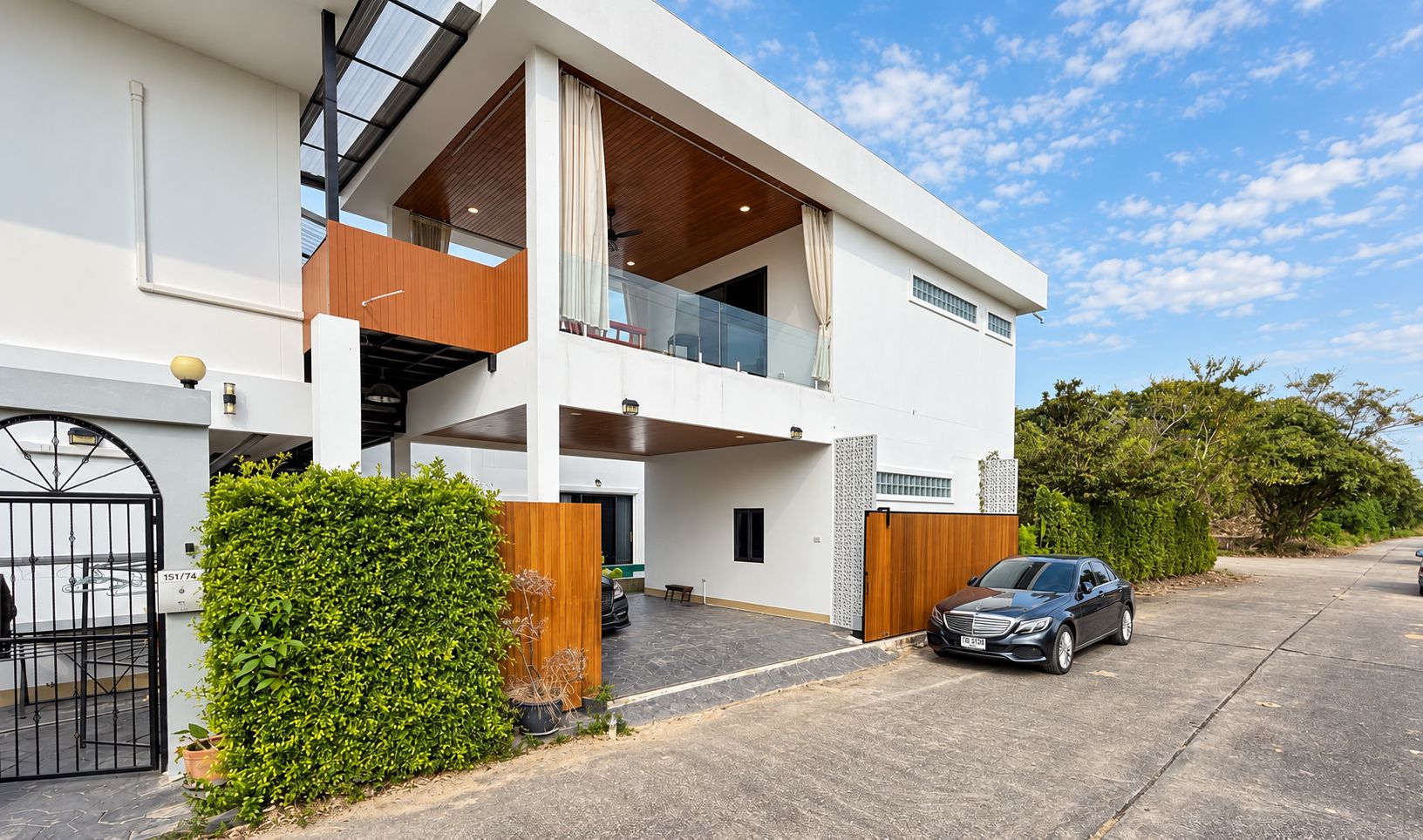 A modern two-story house with a garage, a balcony, and a car parked in front.