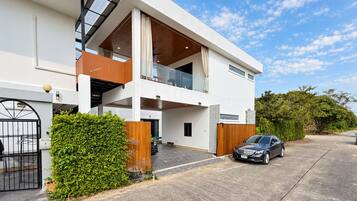 A modern two-story house with a garage, a balcony, and a car parked in front.