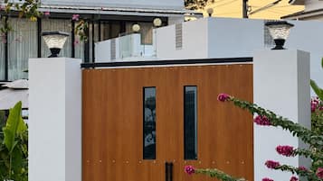 Una puerta de madera con diseño moderno, ubicada frente a una pared blanca con un ventanal pequeño.