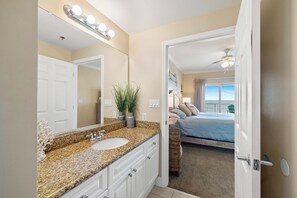 A bathroom with a granite countertop, a white sink, and a mirror with lights. - Seawind 1109 by Liquid Life (Gulf Shores)