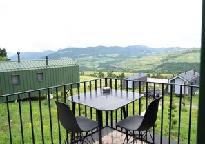 A balcony with a table and chairs, overlooking a green landscape with hills. - Shakaryan Rancho&Restaurant (Dsegh)