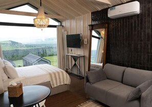 A room with a bed, a sofa, a TV, and a view of the outdoors. - Shakaryan Rancho&Restaurant (Dsegh)