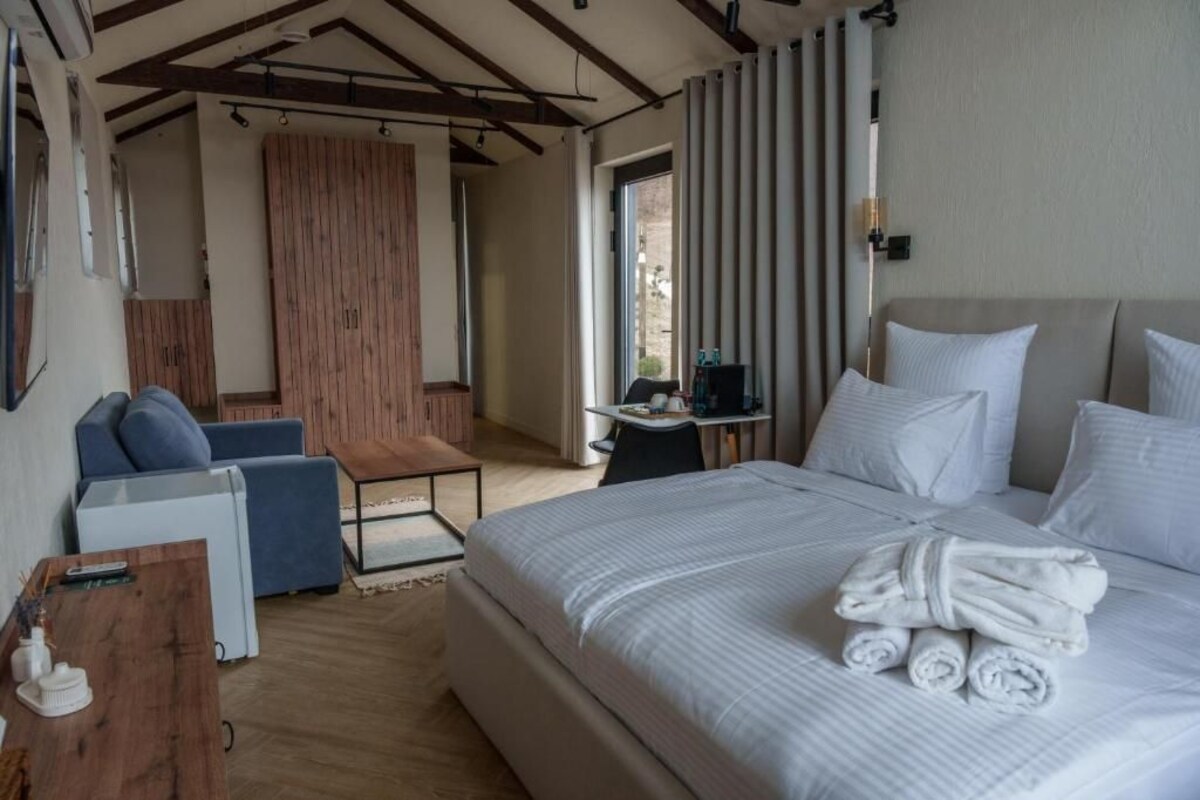 A hotel room with a bed, a desk, a chair, and a view of the outside.