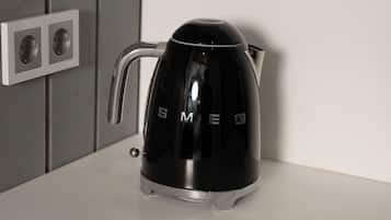 A black electric kettle with a handle on a white countertop.