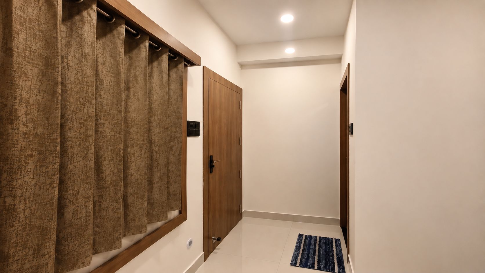A hallway with a wooden wardrobe, a door, and a blue rug.