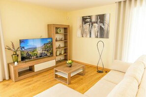 A modern living room with a flat-screen TV, wooden furniture, a coffee table, and a painting on the wall. - Nature Hill 2 by Portugal Active (Viana do Castelo)