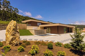 A modern two-story house with a stone facade, a large rock feature, and a well-maintained garden. - Nature Hill 2 by Portugal Active (Viana do Castelo)