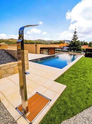 A modern outdoor pool area with a metal structure, a stone wall, and a well-maintained lawn. - Nature Hill 2 by Portugal Active (Viana do Castelo)