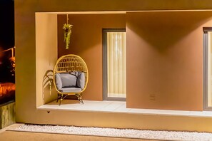 Ein modernes Interieur mit einer hängenden Pflanze, einem gepolsterten Sessel und einem großen Fenster.
