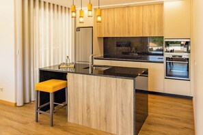 A modern kitchen with a central island, stainless steel appliances, and wooden cabinetry. - Nature Hill 1 by Portugal Active (Viana do Castelo)