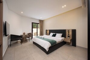 A modern hotel room with a large bed, a TV mounted on the wall, a small round table, and a seating area with a chair. - Lovely Home at Elevens by Spacey #1 (cairo)