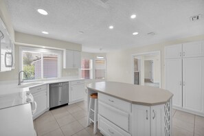 A modern kitchen with white cabinetry, a central island, and a dishwasher. - Sawgrass TPC golf views (Sawgrass)
